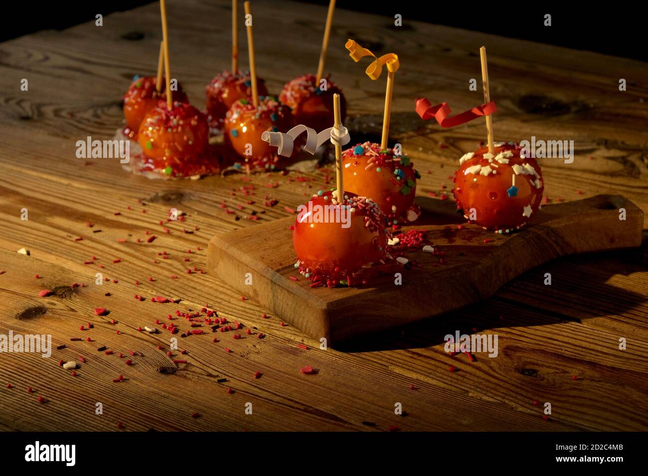 Mele in caramello rosso, decorate con decorazioni su una tavola di legno su sfondo scuro. Concetto di cibo festivo. Foto Stock