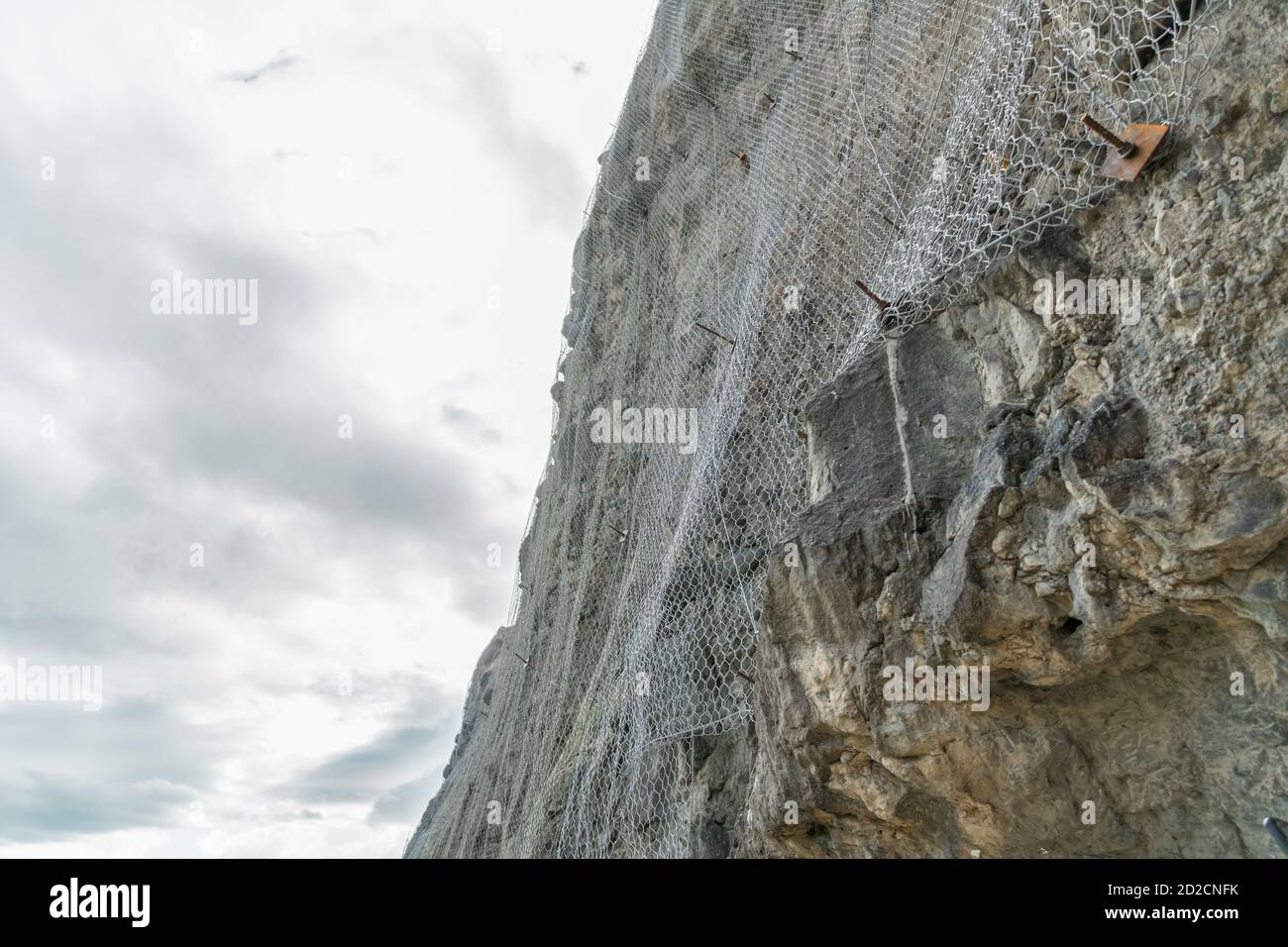 Rete metallica protettiva contro la caduta di pietre contro il cielo con le nuvole. Vardzia, Georgia Foto Stock