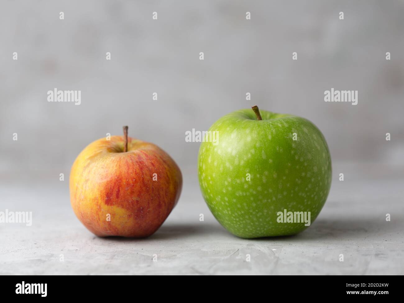 Due mele su fondo verticale di cemento agray, orizzontale Foto Stock