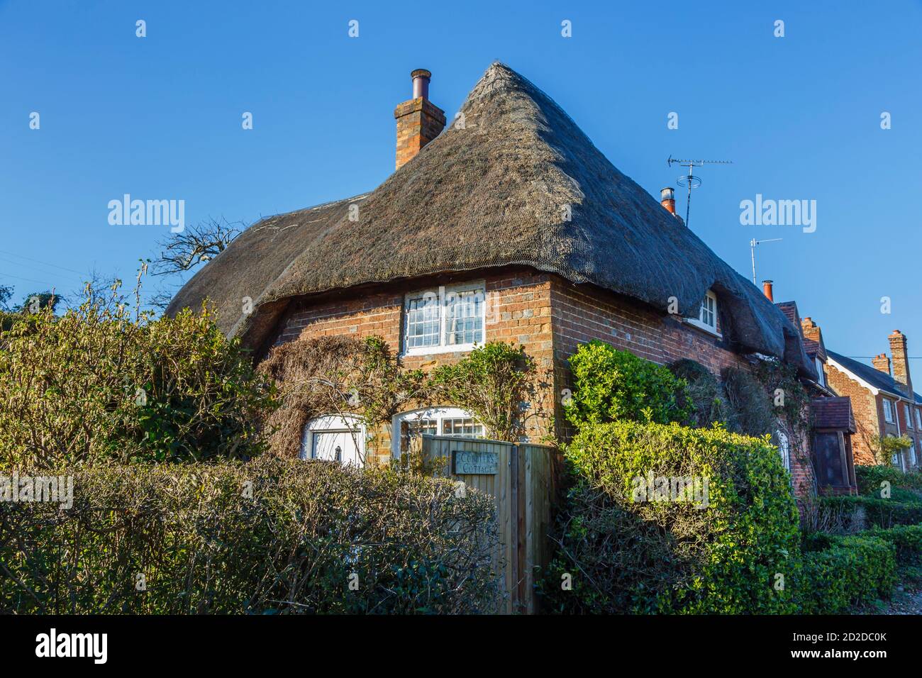 Un tradizionale cottage in mattoni rossi costruito in paglia, Cobbler's Cottage, visto in una giornata di sole nel villaggio di Great Bedwyn, Wiltshire, Inghilterra meridionale Foto Stock