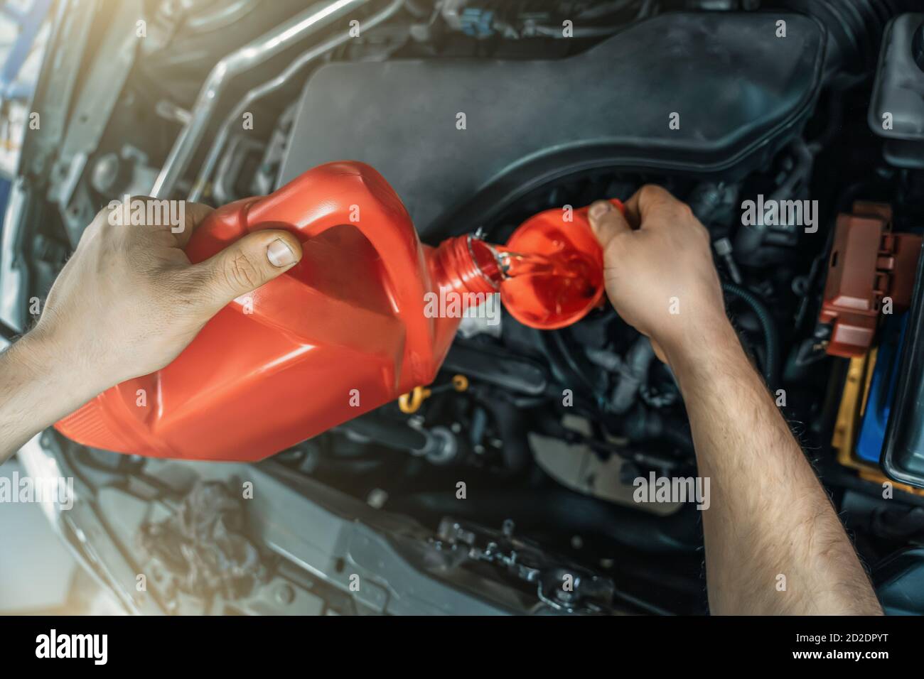 Versare olio motore nuovo dal filtro a carboni attivi nell'imbuto del motore al momento del servizio di assistenza auto, primo piano. Foto Stock