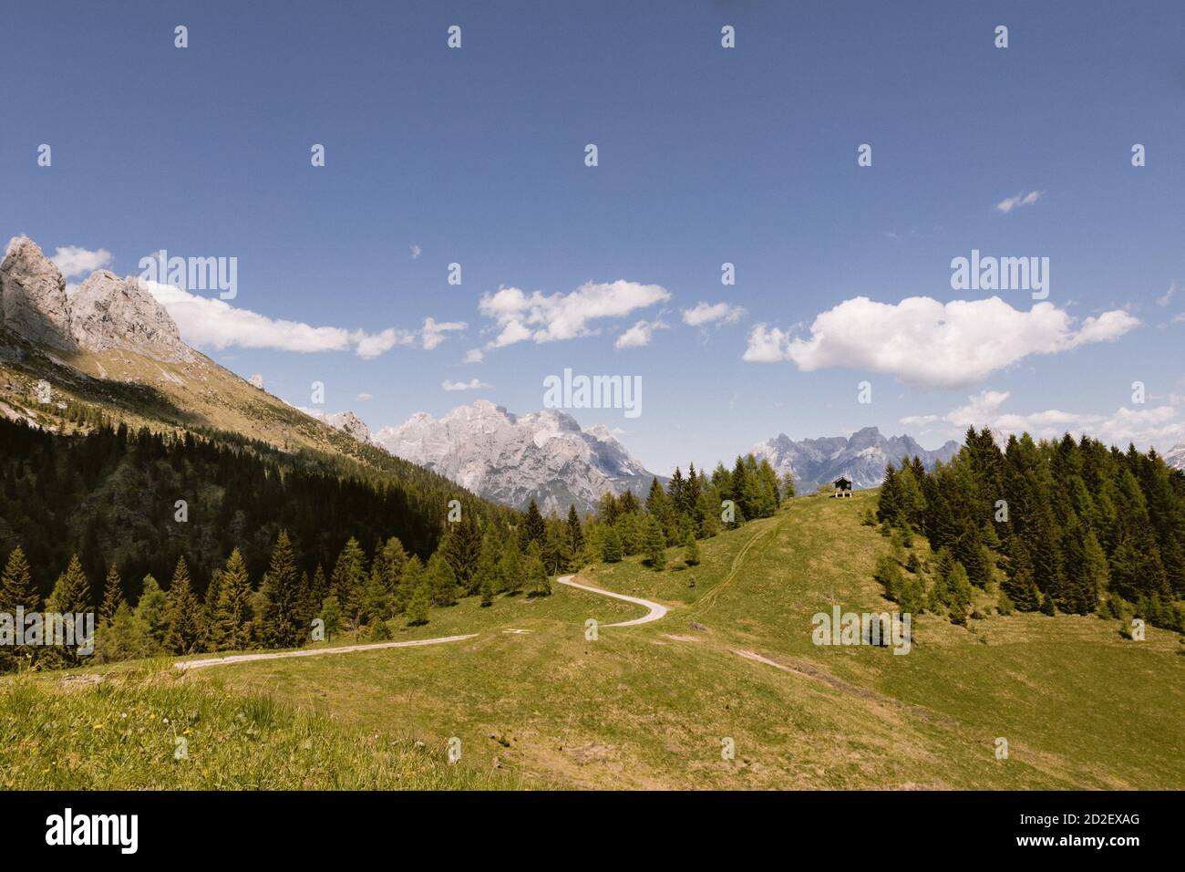 Strada per un piccolo rifugio appartato per pastori sulle Alpi italiane. Paesaggio delle Dolomiti, un prato verde e cielo nuvoloso sulla cima della montagna Foto Stock