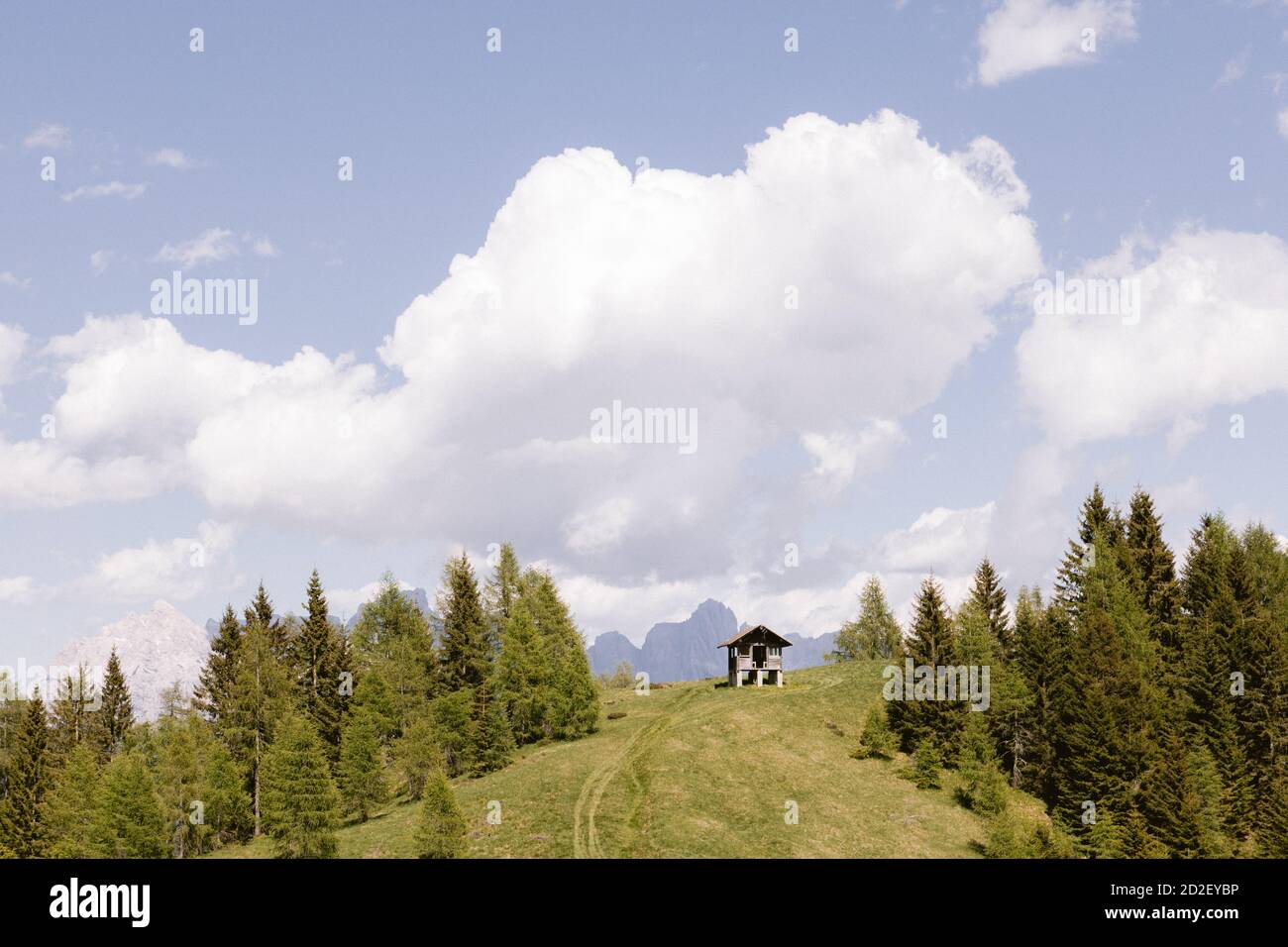 Piccolo rifugio appartato per i pastori sulle Alpi Italiane. Paesaggio delle Dolomiti, un prato verde e cielo nuvoloso sulla cima della montagna vicino ad Agordo Foto Stock