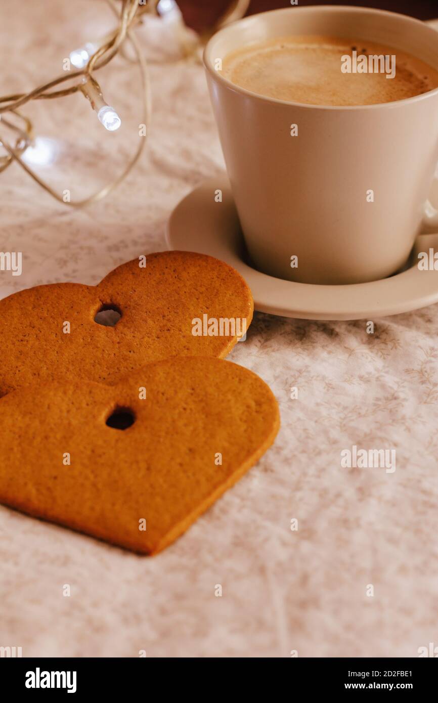 Colpo verticale di una tazza di caffè e biscotti a forma di cuore Foto Stock