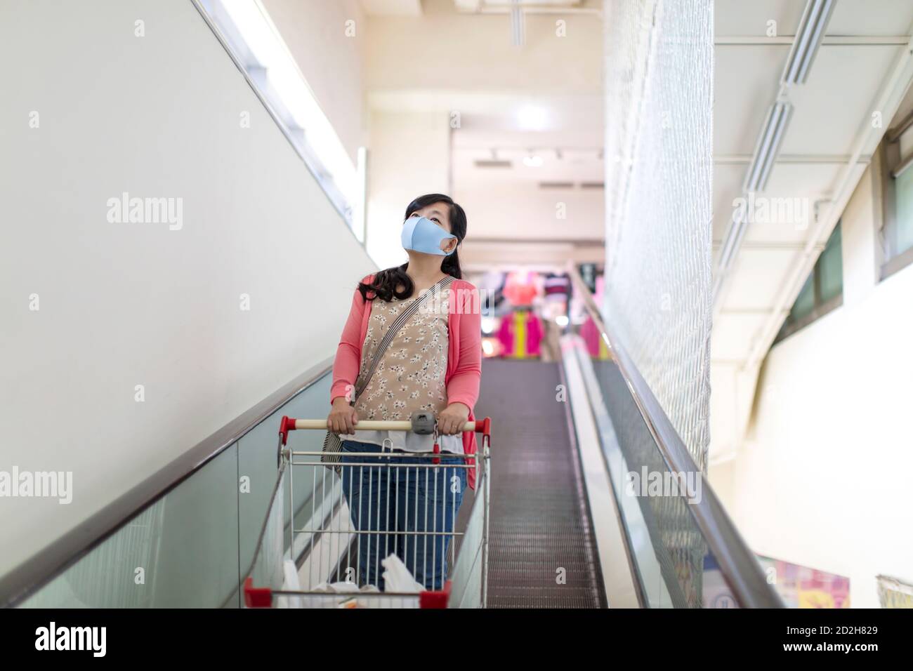 giovane donna che indossa una maschera protettiva nel centro commerciale Foto Stock