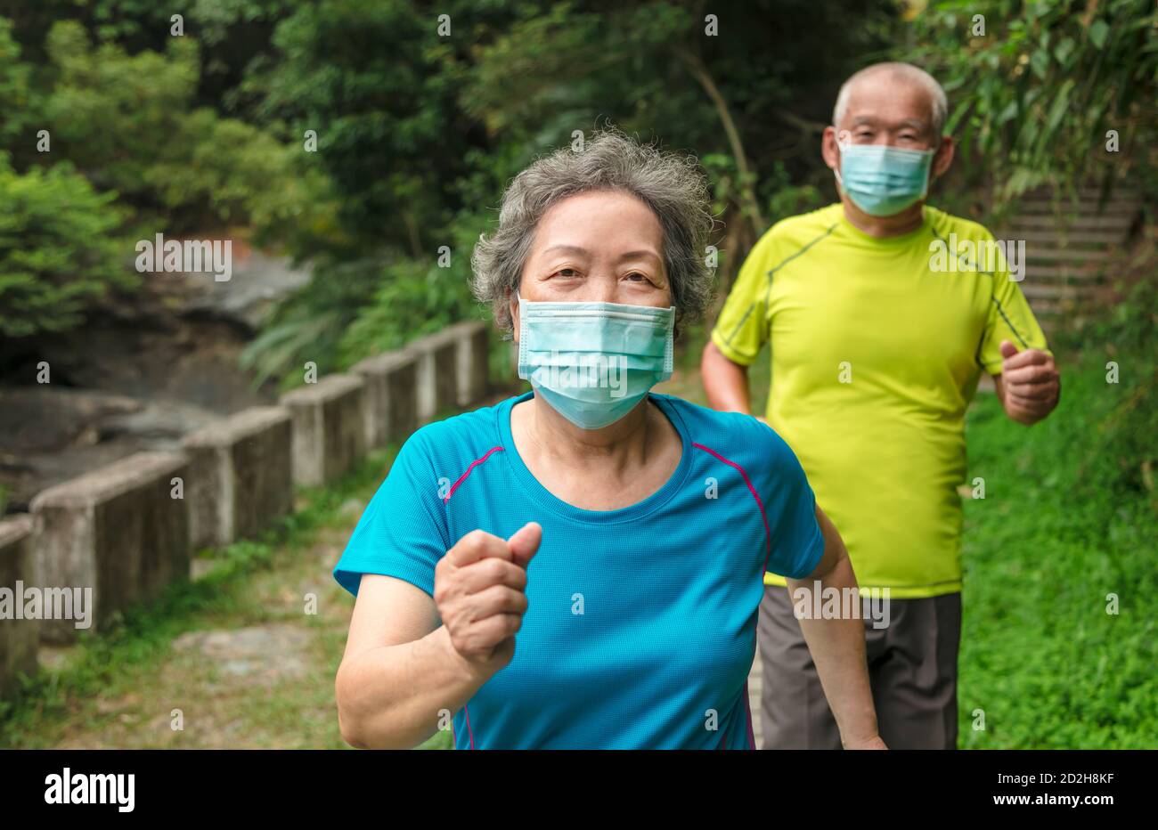 Coppia senior con maschera facciale e passeggiate attraverso il parco naturale Foto Stock