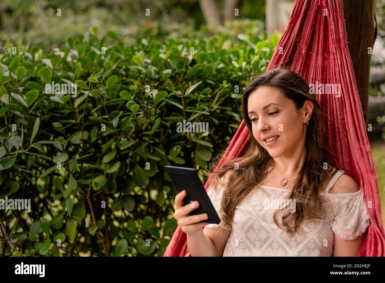 Donna che legge e-book su un amaca Foto Stock