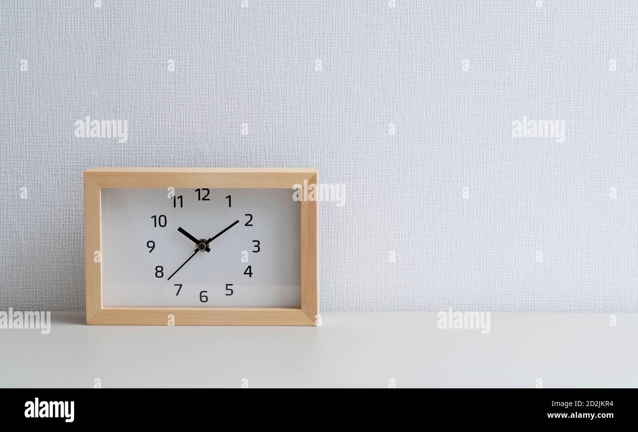 Un orologio quadrato di fronte a una parete bianca Foto Stock