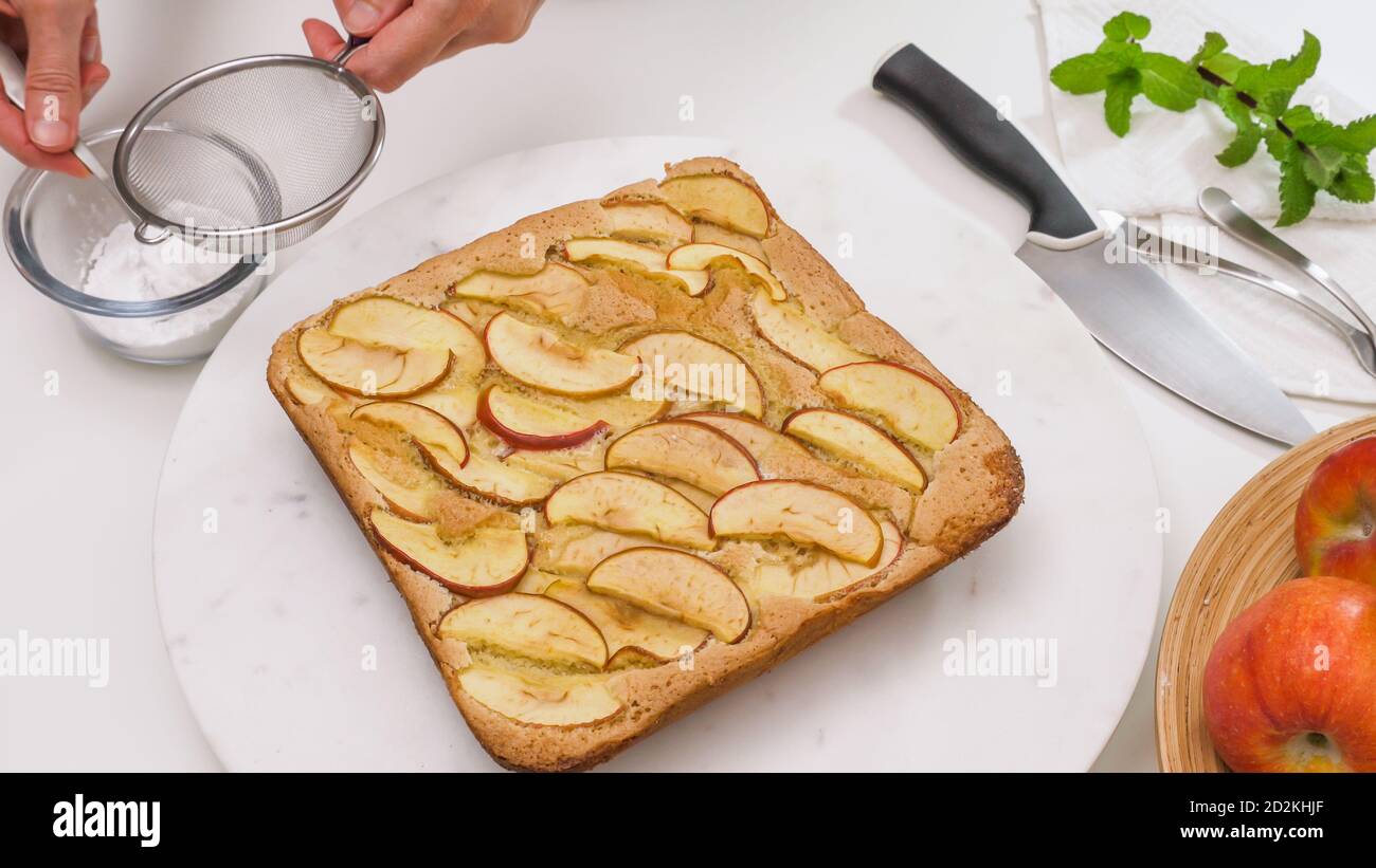 Torta di mele appena sfornata su un tavolo da portata. Condire la torta con zucchero in polvere. Foto Stock