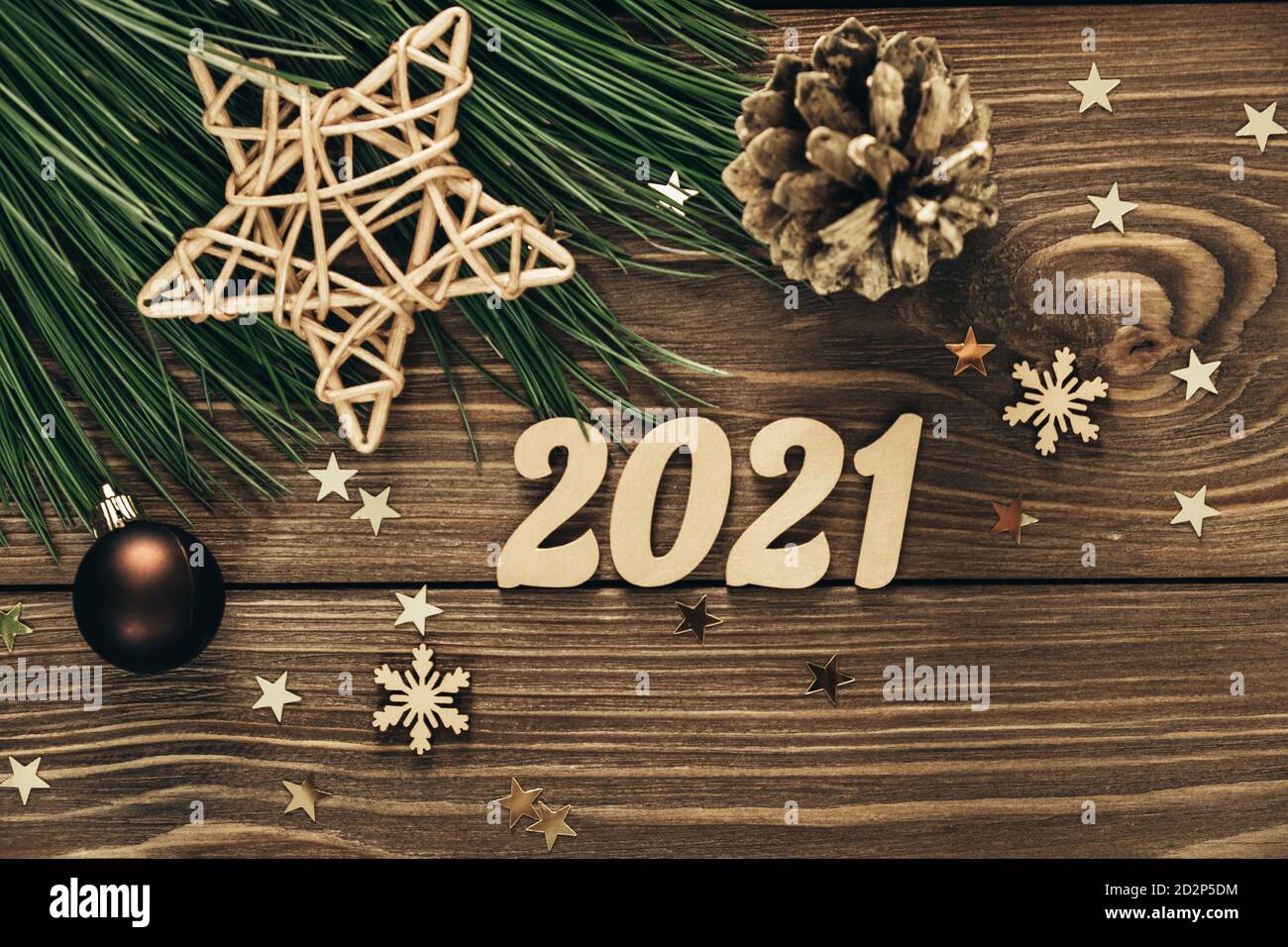 Rami di abete con numeri d'oro, decorazioni e confetti su sfondo ligneo. Anno nuovo 2021. Natale sfondo festivo. Disposizione piatta. Spazio di copia. Foto Stock