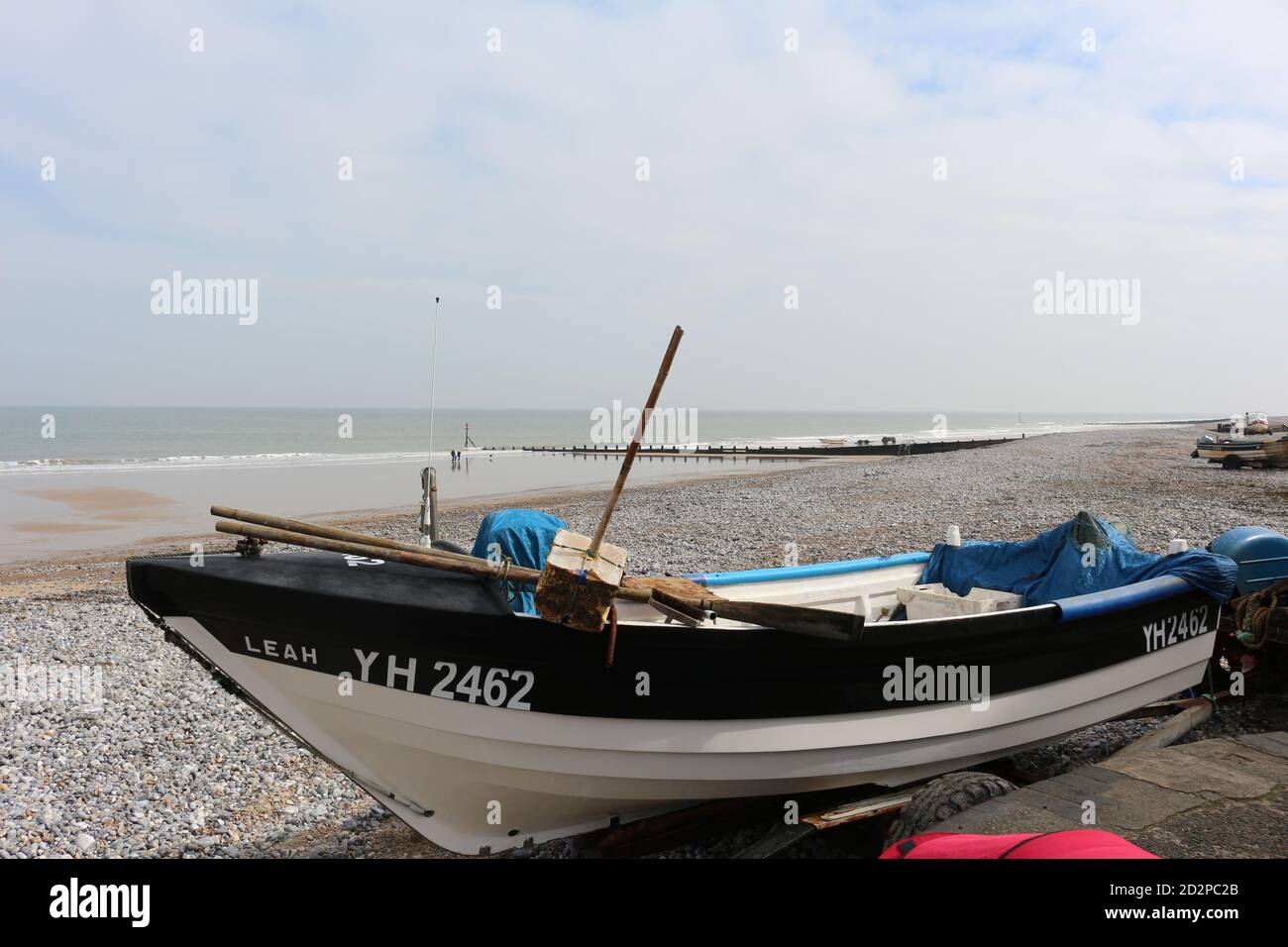 Barche di pescatori sulla spiaggia di sabbia di Cromer in una soleggiata giornata invernale, si scontrano con le dolci onde che si infrangono sulla spiaggia Foto Stock