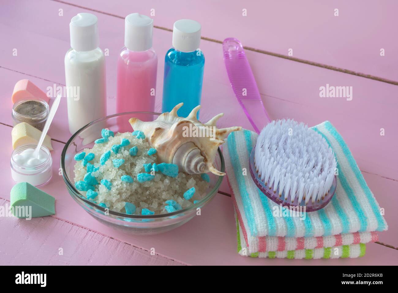 Accessori da bagno su sfondo rosa in legno. Spazzola massaggio e sale marino per il corpo. Vari prodotti per la pulizia e la cura del corpo. Concetto di spa Foto Stock