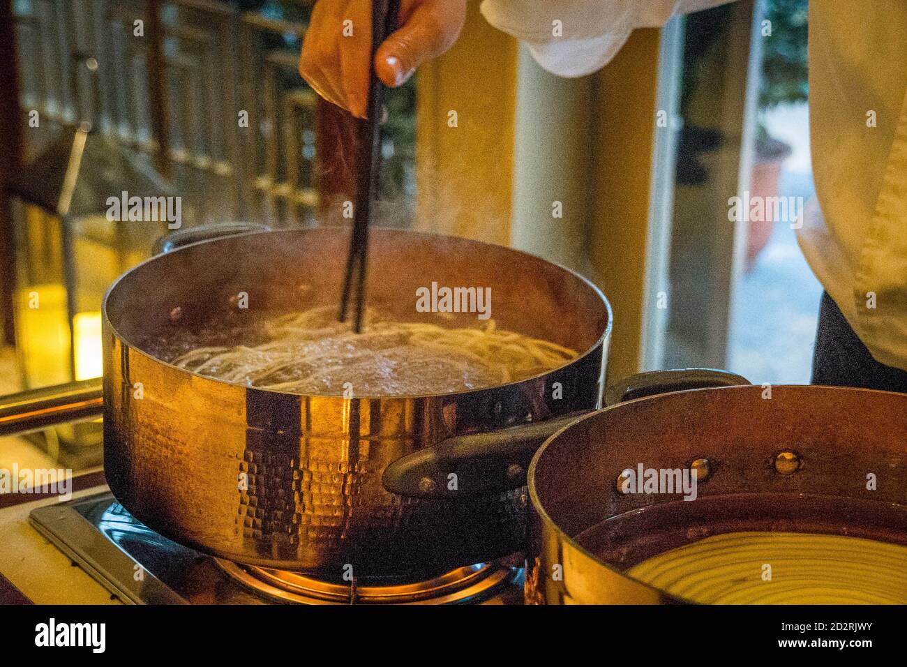 uno chef cinese che cucina noodle cinesi in una cucina dal vivo stazione Foto Stock