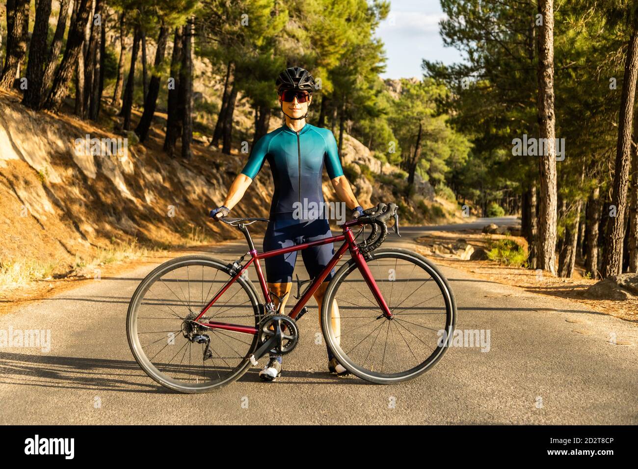 donna matura allenando la bici da strada, arrampicandosi su una strada di montagna, mostrando la bici sulla strada Foto Stock