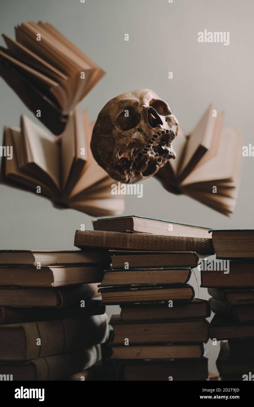 Aprì libri e spaventoso cranio umano che si levitava su un mucchio di vecchi libri impilati Foto Stock