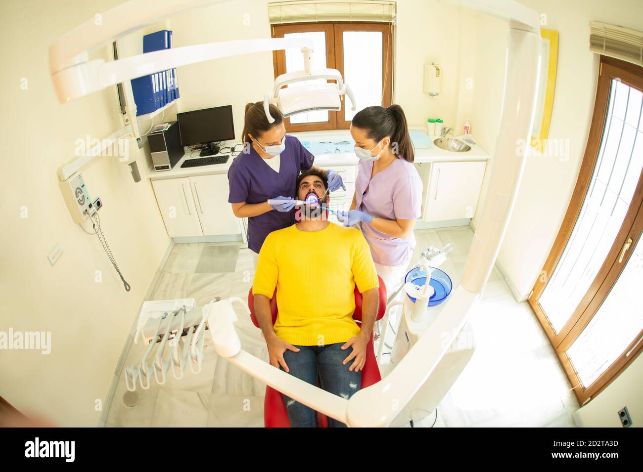 Dentista e assistente che tiene gli strumenti per curare i denti del paziente Foto Stock