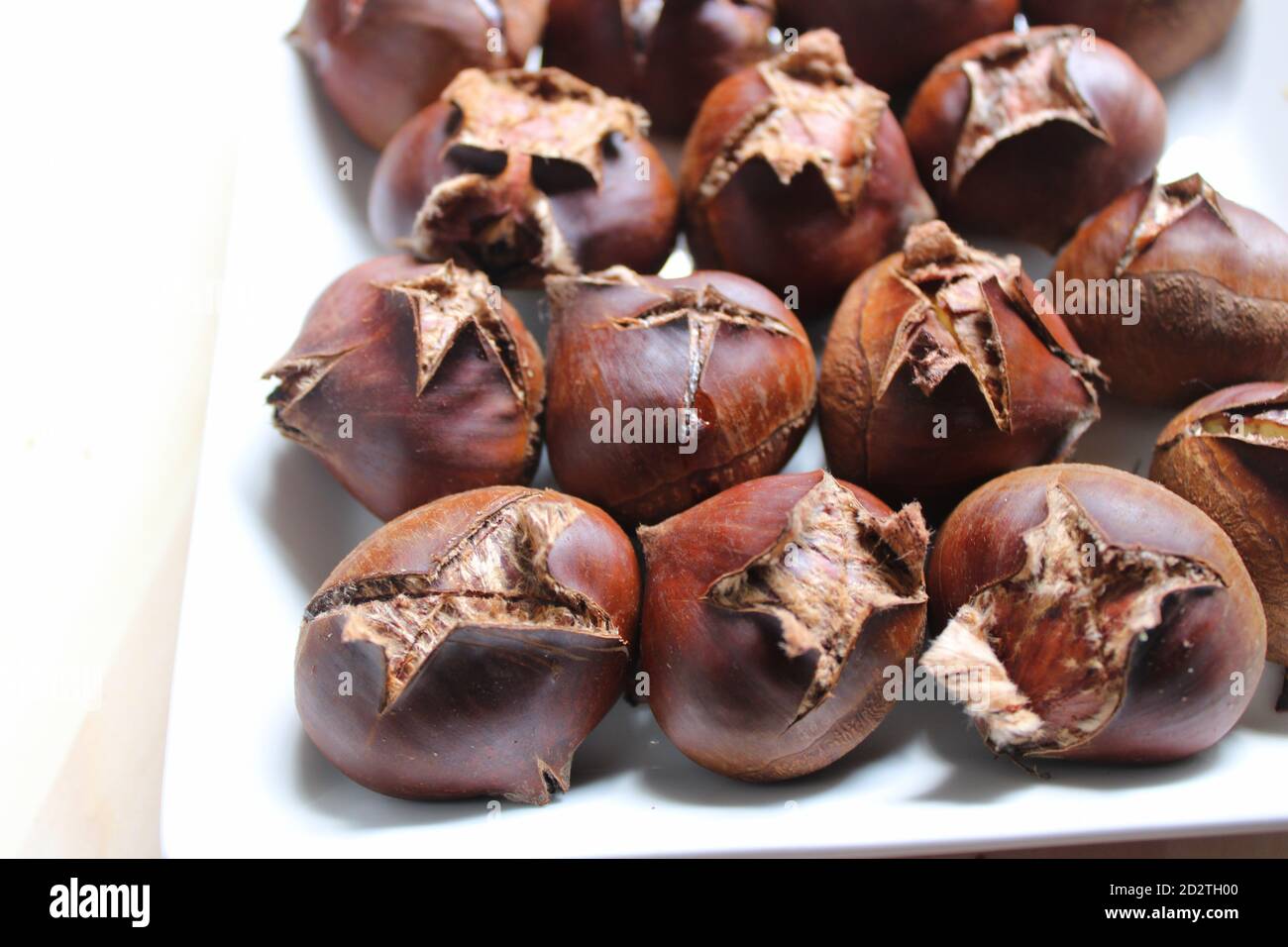 Arrostire le castagne su un piatto di portata bianca Foto Stock