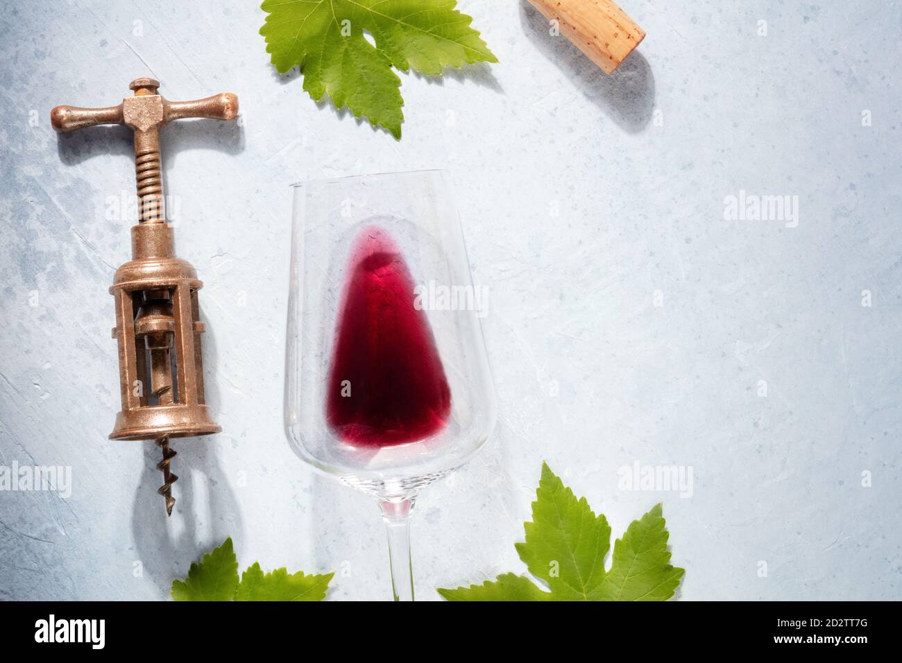 Vista dall'alto del modello di design Wine con una posizione per il testo. Bicchiere di vino rosso, cavatappi vecchi e foglie di vite, colpo dall'alto verso il basso su uno sfondo chiaro Foto Stock