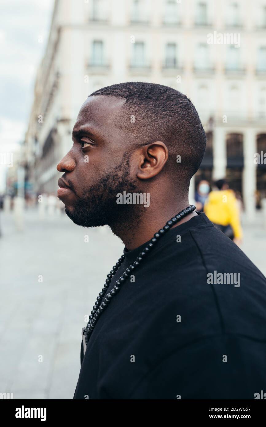 Vista laterale ritratto di un uomo nero serio che guarda via dentro paesaggio urbano Foto Stock