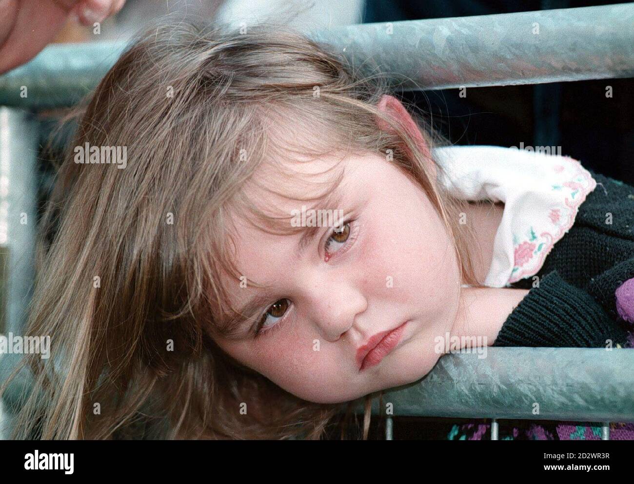 Stephanie i'Anson di 5 anni sembra abbastanza miserabile, come attende che la Brigata del fuoco locale per arrivare, per liberarla. Stephanie era determinato ad avere una buona vista della regina nella sua città natale di Spennymoor, Co Durham, Ma la sua testa era bloccata in fretta nella barriera per tenere indietro le folle, appena prima che la regina arrivasse il vigile del fuoco ha rilasciato la sua testa e ha ottenuto una vista molto buona dopo tutto. Foto Stock