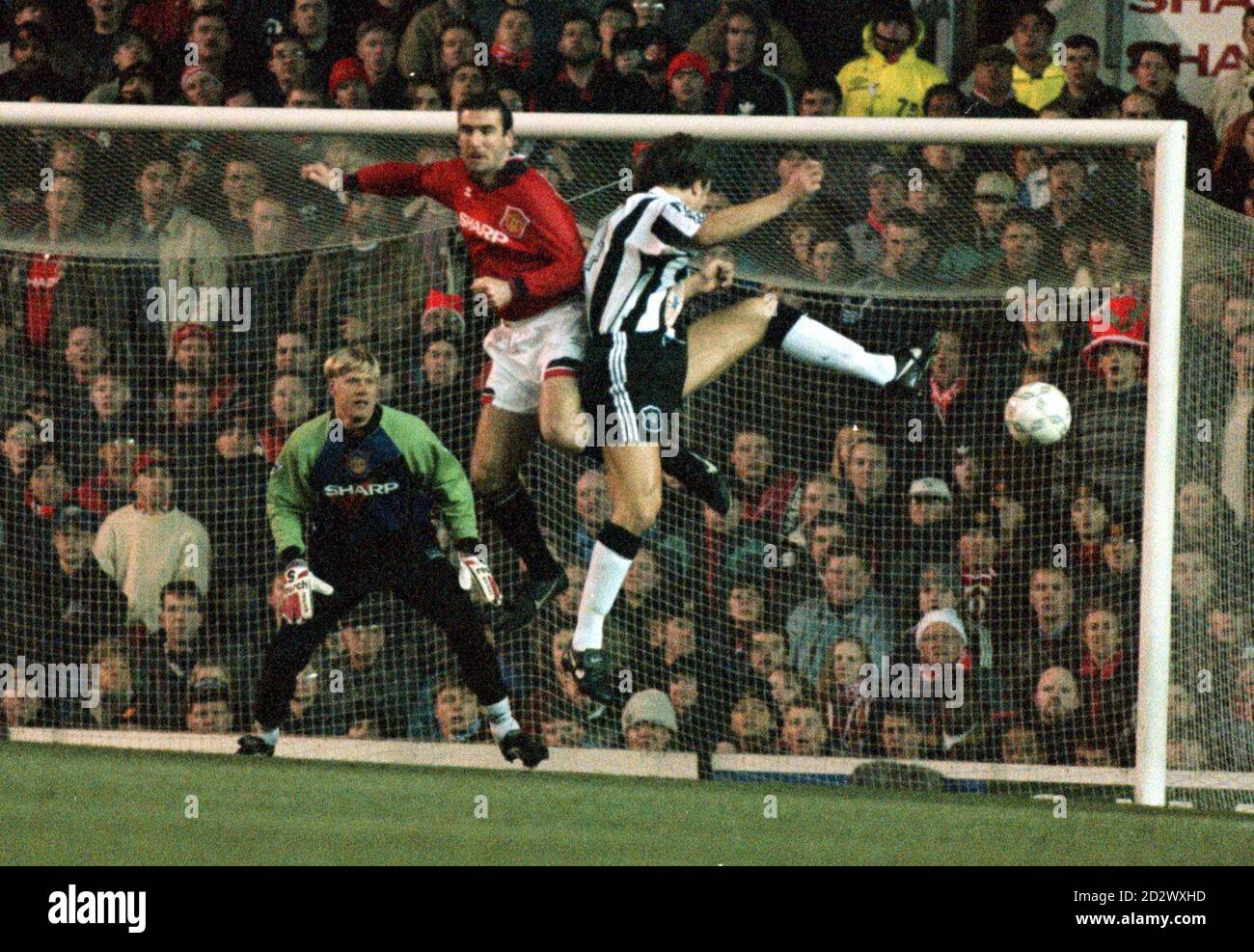 Eric Cantona di Manchester Utd e David Ginola di Newcastle sono seguiti in  una sfida aerea, da Peter Smeichel, nella partita di premiership di stasera  (Mer) a Old Trafford Foto stock -