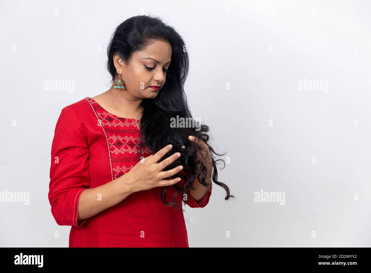 Ritratto di donna indiana con le dita nei suoi lunghi capelli, capelli scuri, sfondo bianco, studio interno girato, area copia spazio. Foto Stock