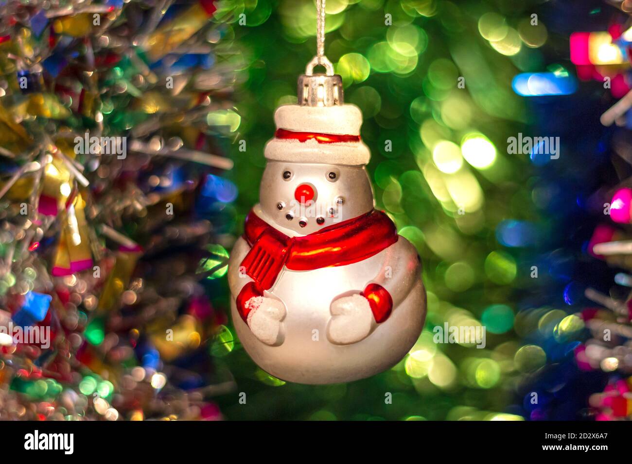 Giocattolo di Capodanno sovietico in vetro d'epoca (pupazzo di neve) sullo sfondo di un albero di Natale e colorato e luminoso tinsel. Foto Stock