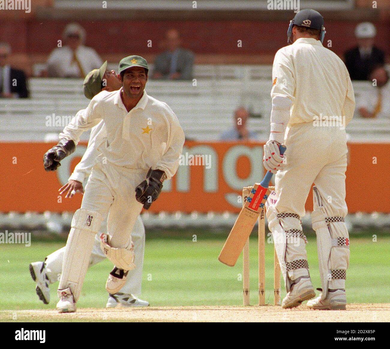 Inghilterra il capitano di prova Michael Atherton (a destra) si gira in modo inadeguato verso il padiglione dopo essere stato catturato fuori dal bowling di Mushtaq Ahmed per 64 corse, il wicketkeeper pakistano Rashid Latif (a sinistra) gode il momento, durante l'ultimo giorno del primo test di Cornhill a Lords. Foto di Tony Harris/PA. Foto Stock