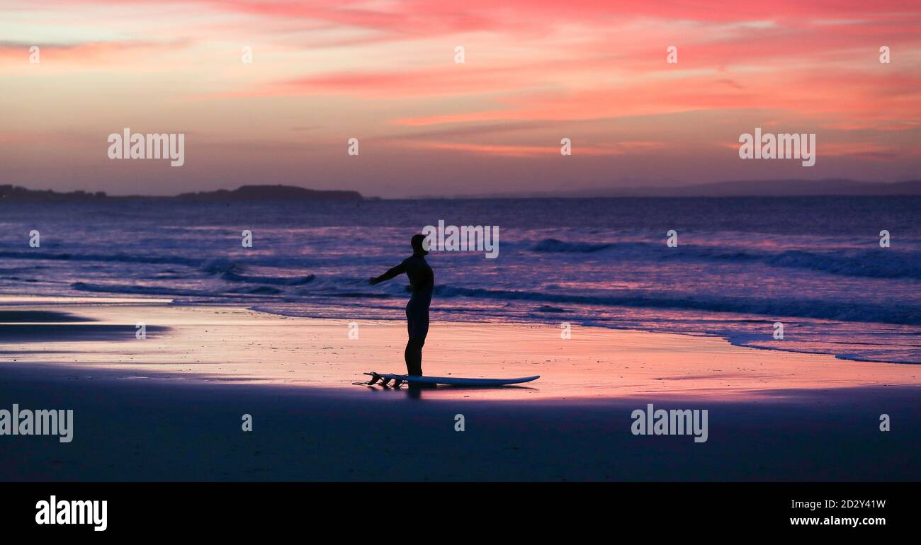 Bournemouth, Regno Unito. 7 ottobre 2020. Un surfista si porta in acqua al largo di Bournemouth sulla costa del Dorset all'alba. Credit: Richard Crease/Alamy Live News Foto Stock