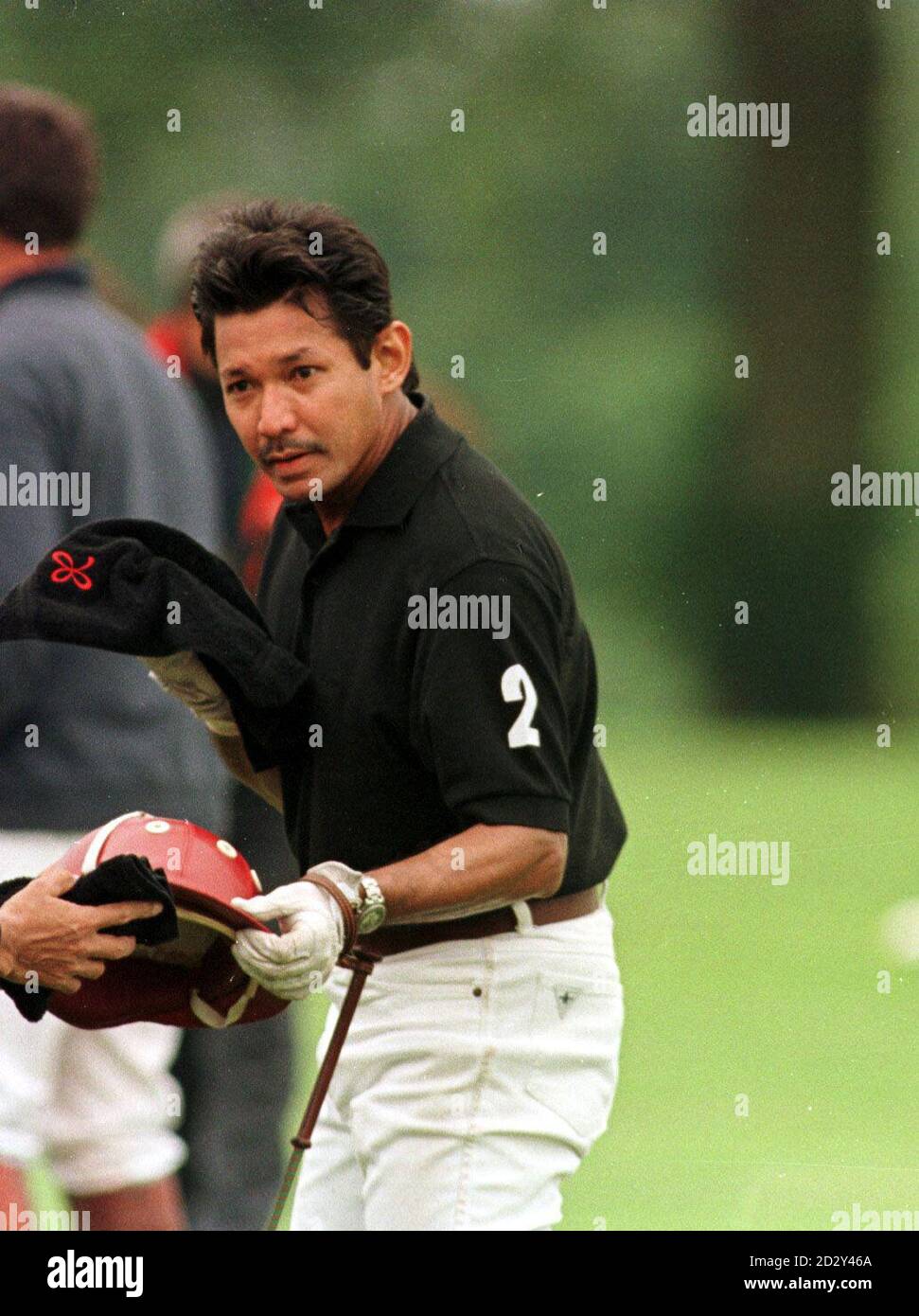 S.A.R. il principe Jefri Bolkiah, fratello del sultano di Brunei, consegna la sua divisa ad un aiutante dopo aver giocato nel Trofeo Asprey Polo 1997 nel Cirencester Park. Foto Stock
