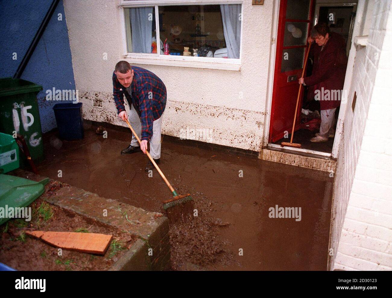 Anthony Saint e Val Hanson-Spule puliscono fango e acqua dalla loro casa a Wordsworth Gardens, Rhydfelin, Galles del Sud. Gran parte del paese stava affrontando il potenziale caos del traffico, in quanto gravi inondazioni e venti forti hanno gravemente colpito le strade di quello che è già stato chiamato Delay Day. Foto Stock