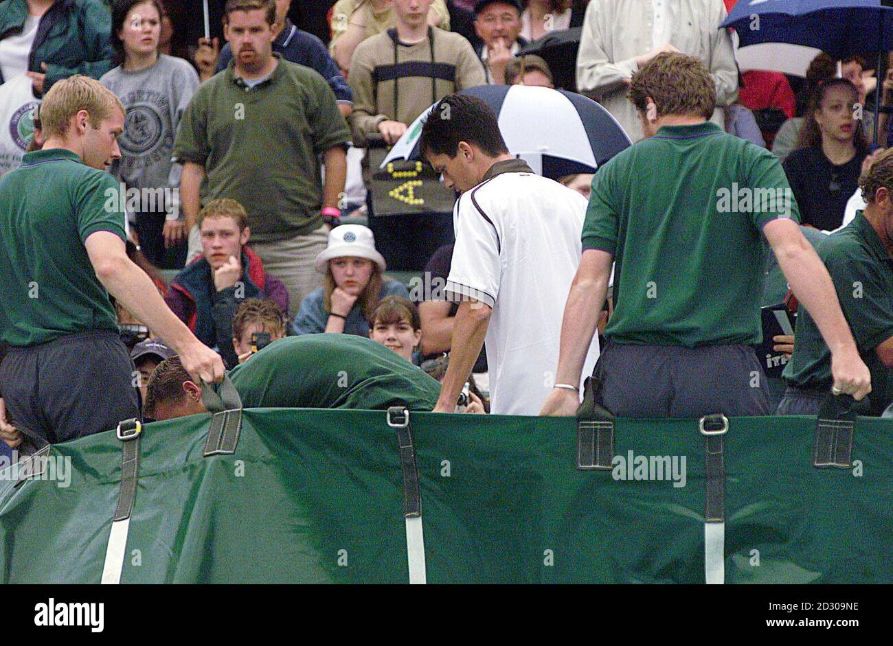 Il britannico No.1 Tim Henman (centro) lascia il campo uno dopo la pioggia ha interrotto la partita per la seconda volta durante il suo quarto finale di partita contro Cedric Pioline di Francia ai campionati di tennis di Wimbledon 1999. Foto Stock