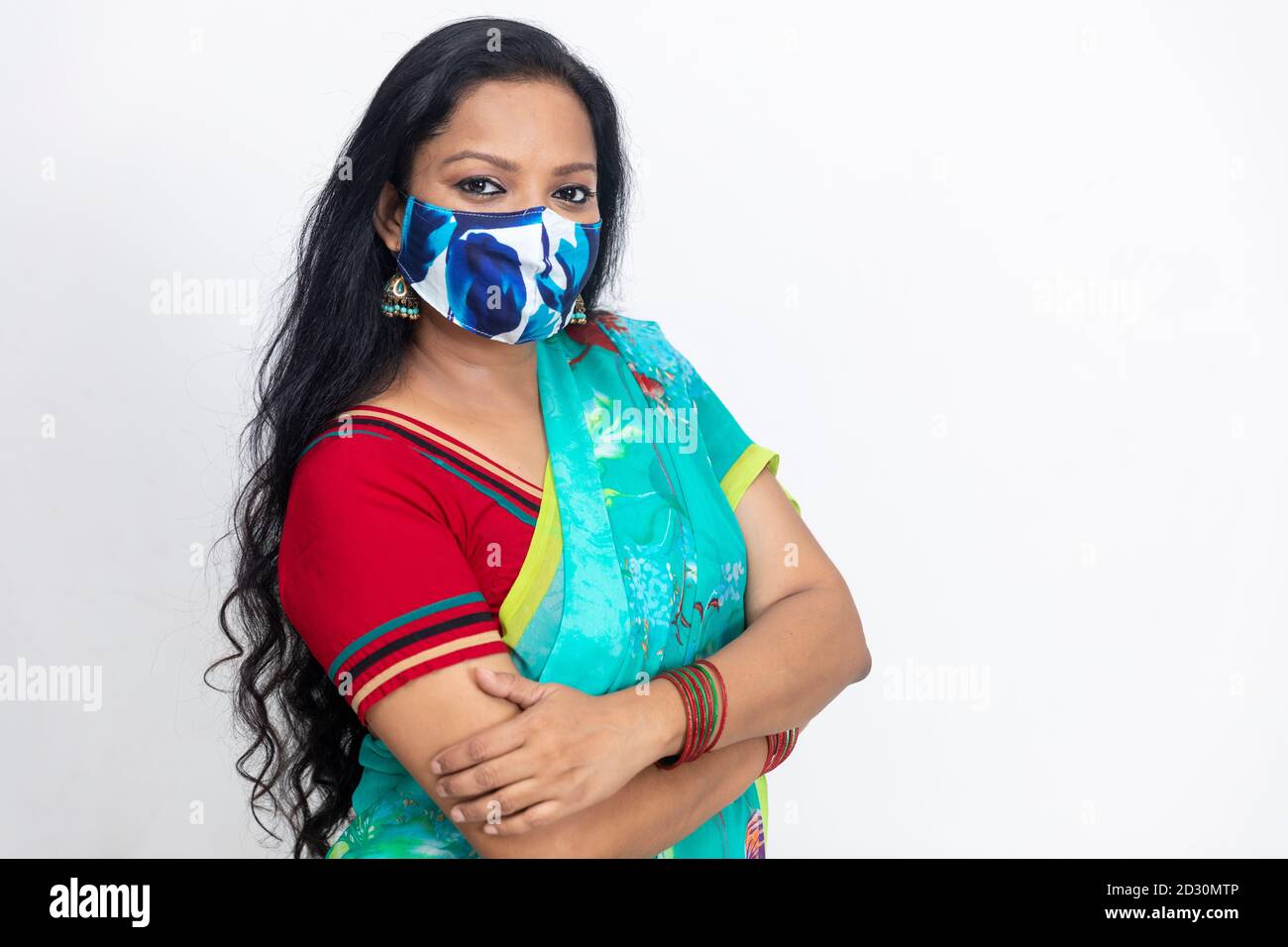 Ritratto di una donna indiana in abito tradizionale indiano, con maschera di protezione Covid 19 e in piedi contro la parete bianca, ritratto in studio, Foto Stock