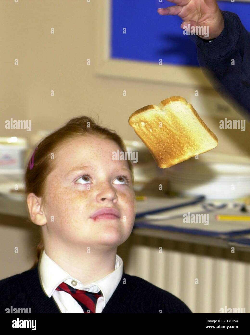 Maggie Molloy, 10 anni, guarda mentre il compagno di classe JJ Warren-Markland fa cadere un pezzo di brindisi alla Good Shepherd RC Primary School di Londra. I bambini della scuola stanno partecipando al Lurpak Tumbling Toast Test. *...- un esperimento per vedere se il pane tostato è più probabile cadere il lato del burro giù. Foto Stock