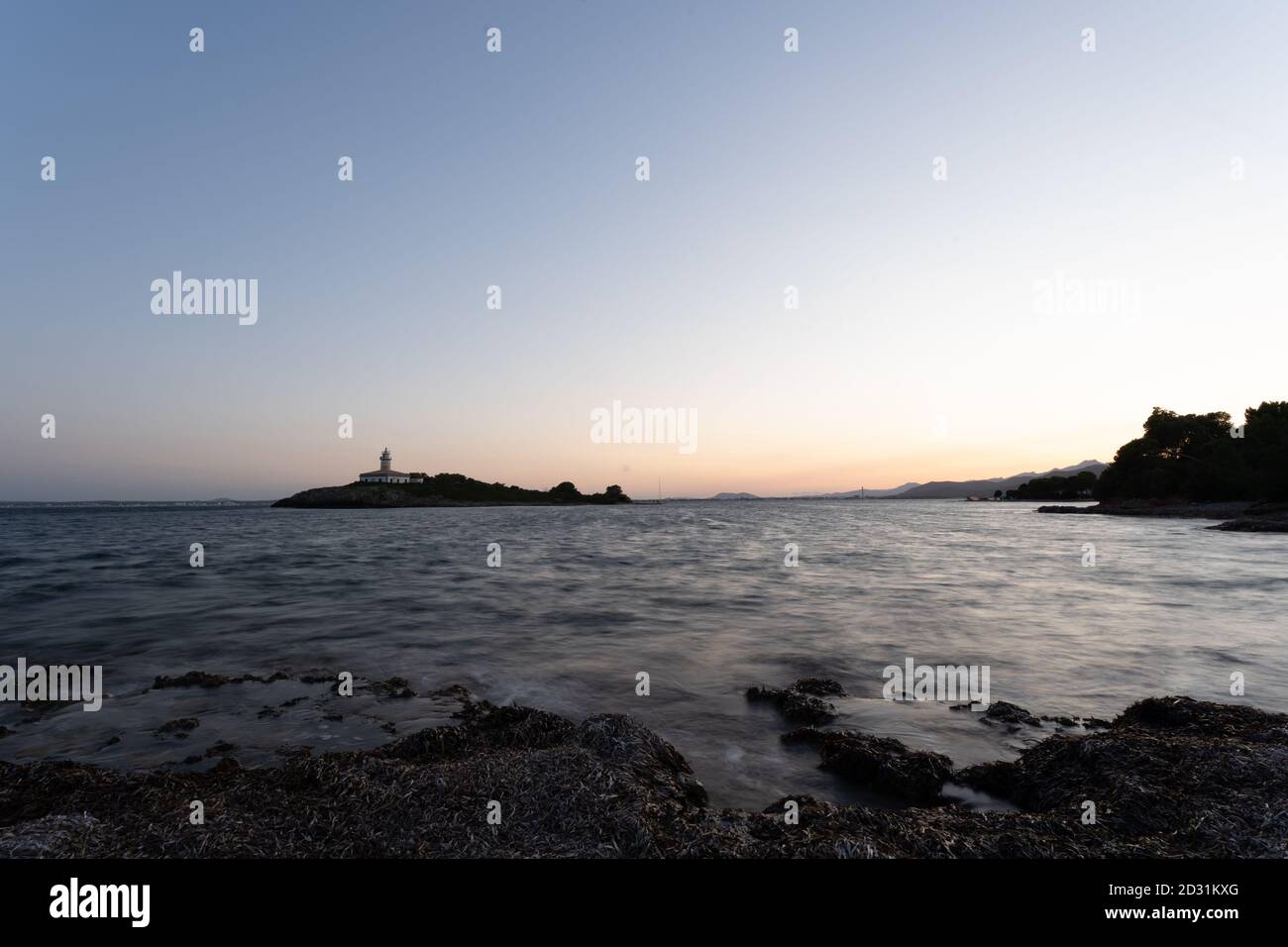 Il faro Aucanada, nella baia di Alcudia, Maiorca, Spagna, in una notte estiva e cielo limpido. Immagine tratta dalla spiaggia, proprio di fronte. Foto Stock