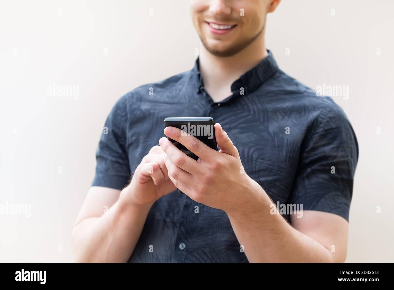 Uomo che usa lo smartphone mobile, primo piano. Immagine di un giovane uomo che usa uno smartphone mobile e sorridente. Foto Stock
