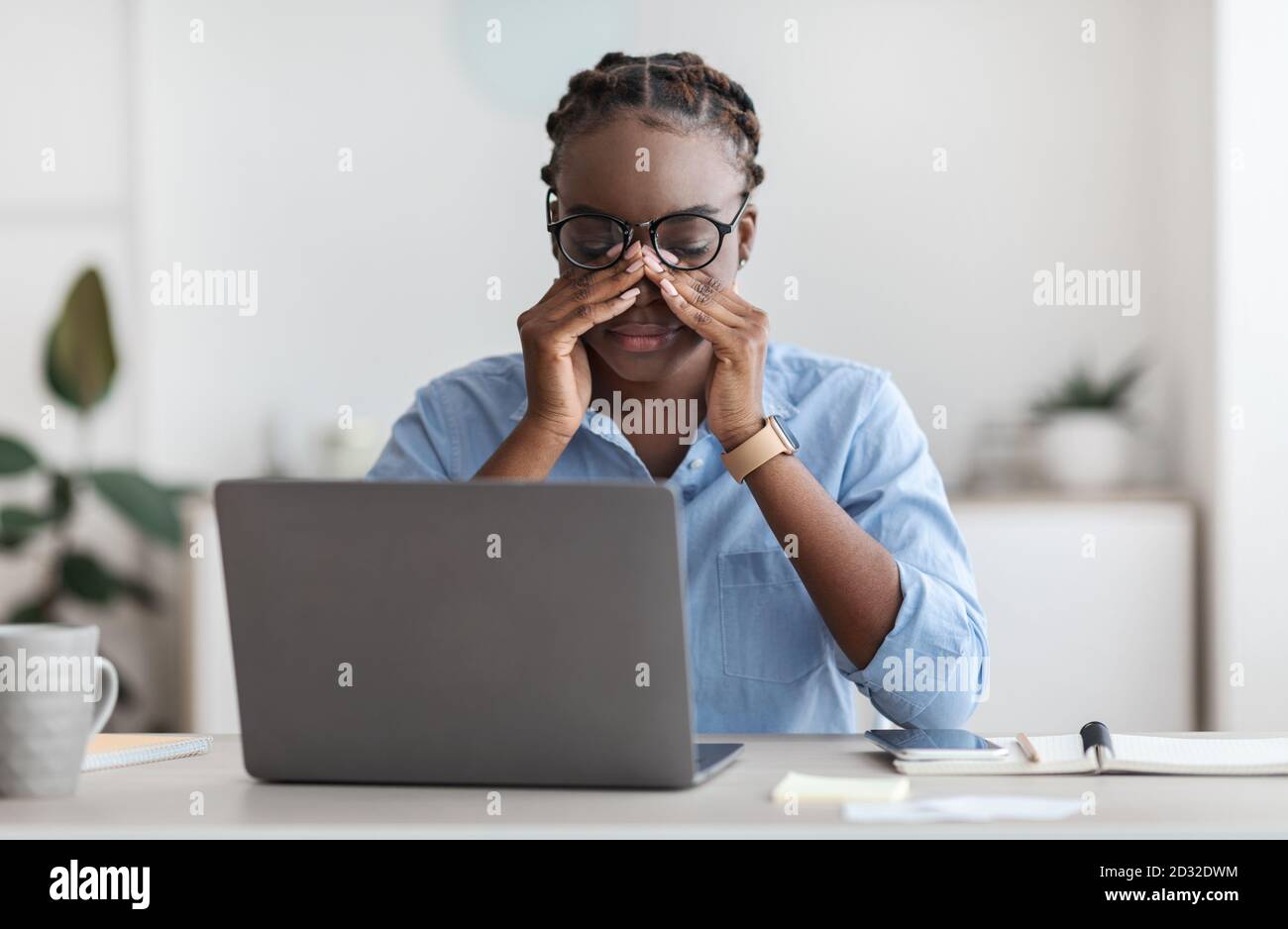Affaticamento degli occhi. Stanco African Female Office Worker seduto sul posto di lavoro massaggiando Nosebridge Foto Stock
