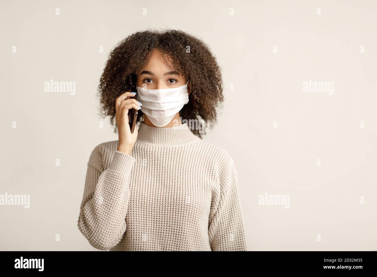 Connessione sociale e distanza durante l'epidemia di virus. La donna millennial afroamericana parla al telefono Foto Stock