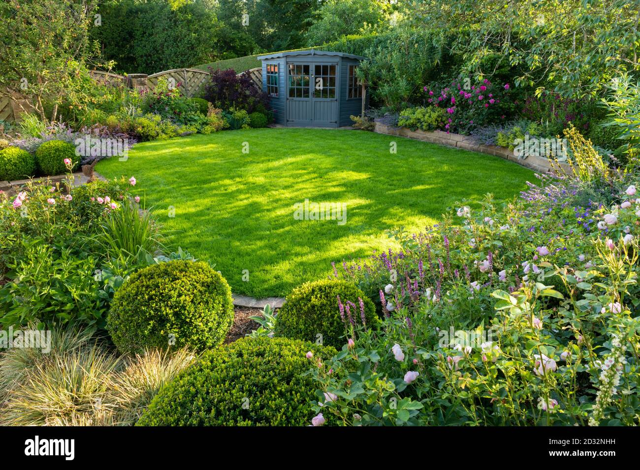 Giardino privato paesaggistico e soleggiato (design contemporaneo, fiori estivi, piante di confine, arbusti, capannone, muretto, prato) - Yorkshire, Inghilterra UK Foto Stock