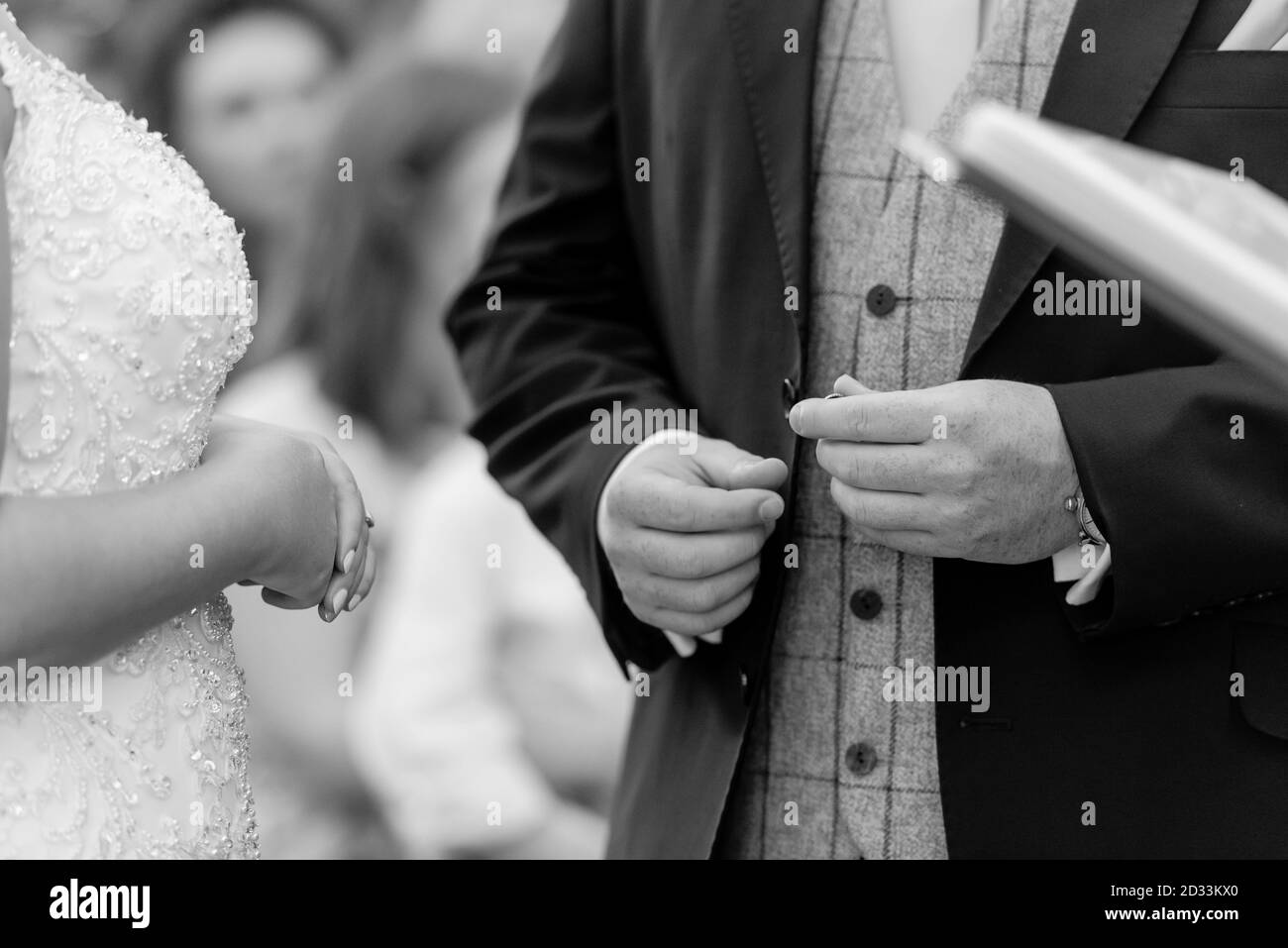 Primo piano di scambio dell'anello di nozze in nero e bianco grooms mano Foto Stock