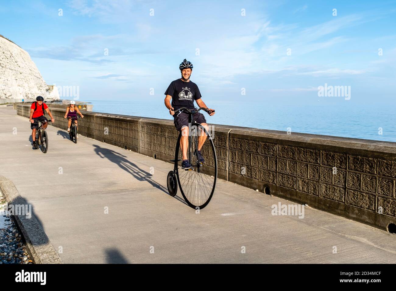 A Man Riding A Penny Farthing Bicycle lungo la passeggiata Undercliff, Rottindean, East Sussex, UK. Foto Stock