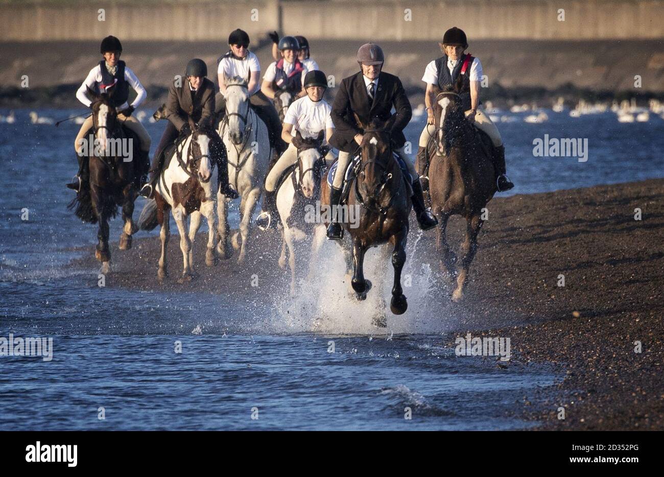 Cavallo-piloti prendere parte dei crociati Chase al tramonto sulla spiaggia di Musselburgh all'inizio della settimana di Festival di Musselburgh. Foto Stock