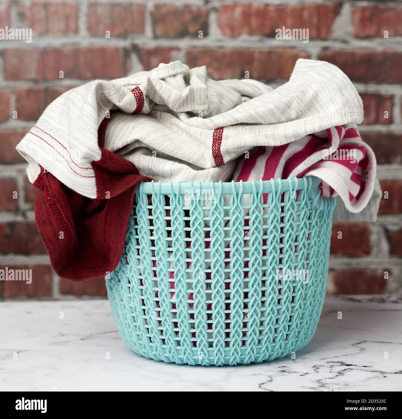 cesto di lavanderia e lavanderia ripiegata, fondo di mattoni marroni, primo piano Foto Stock