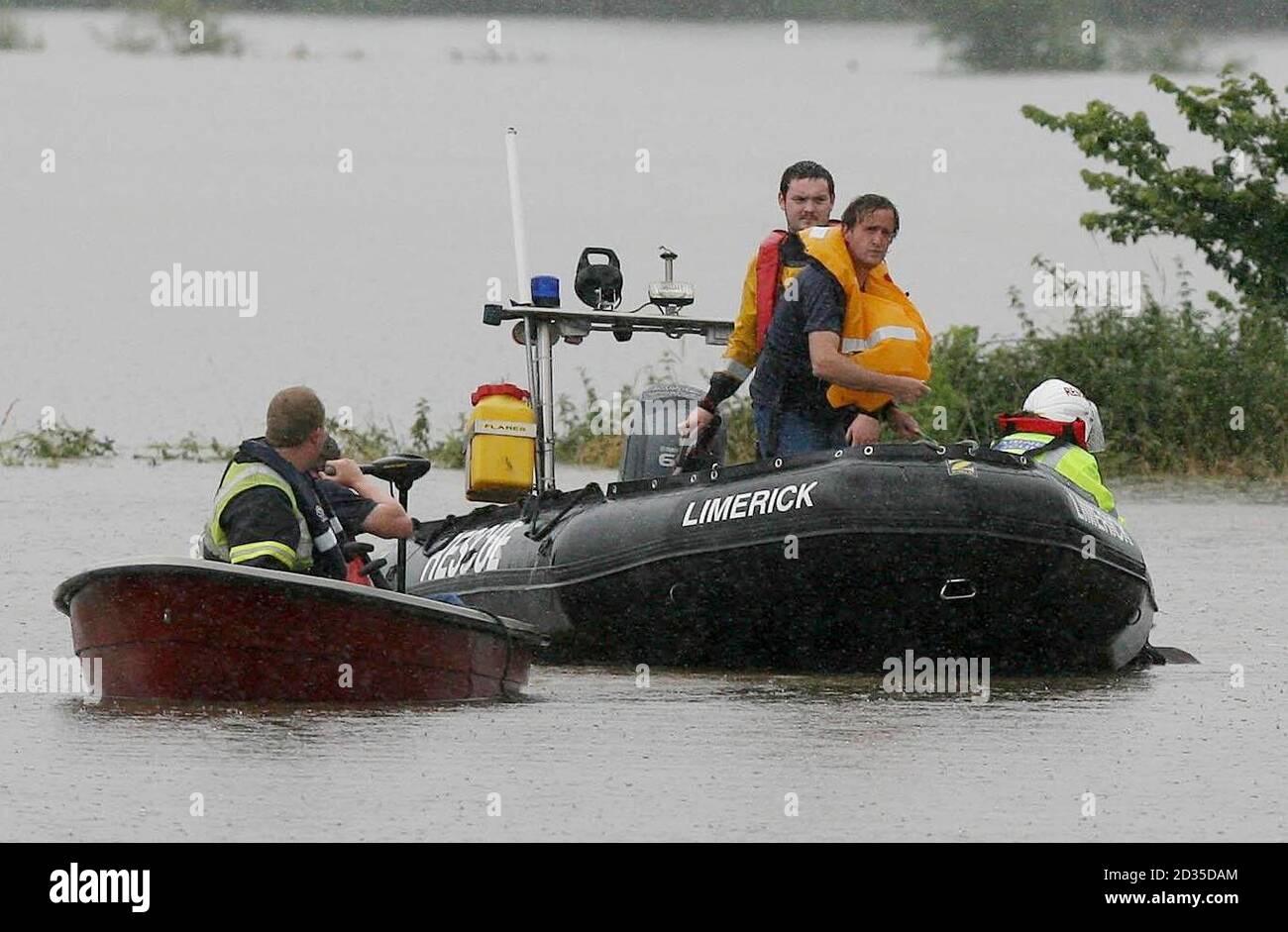 Un agricoltore salvato dalle acque alluvionali (t-shirt marina/bib arancione) si erge sulla barca di salvataggio a Newcastle West, Co Limerick dopo che il fiume Arra ha scoppiato le sue rive ieri notte. Foto Stock
