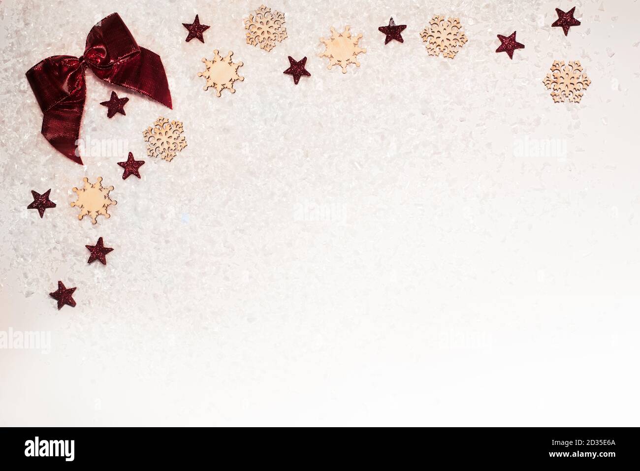 Sfondo natalizio, con stelle glitter, arco rosso, fiocchi di neve in legno e neve - sofisticato, di lusso - spazio di copia Foto Stock