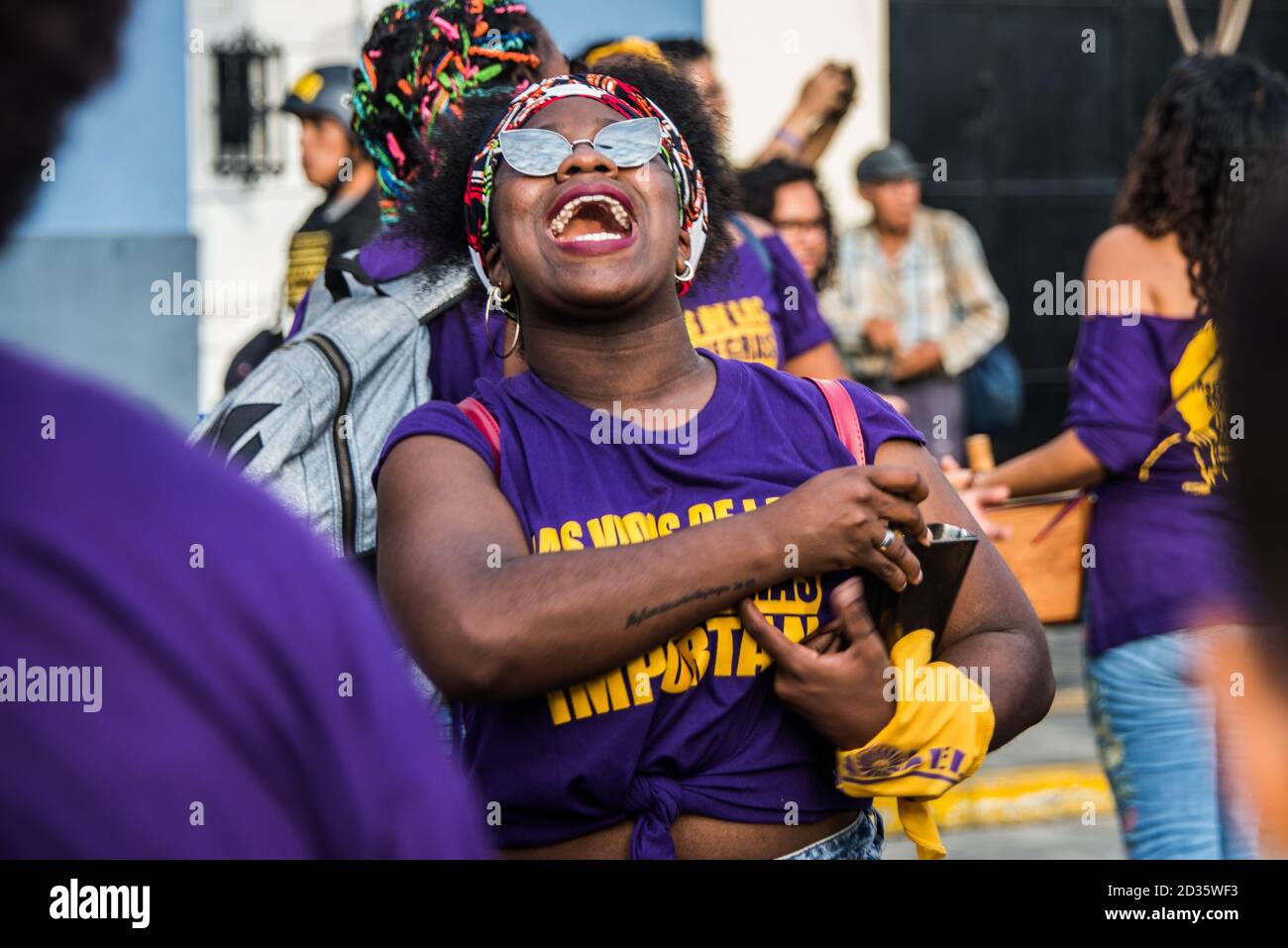 Una donna nera che indossa una t-shirt Black Lives Matter partecipando, marciando e ballando per le strade di Lima, Perù su International Womens Day2020 Foto Stock