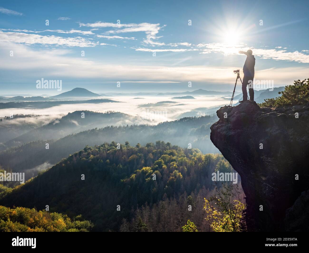 Il fotografo scatta foto con la fotocamera sulle colline del mattino. Fotografo di paesaggi naturali con attrezzatura fotografica su roc Foto Stock