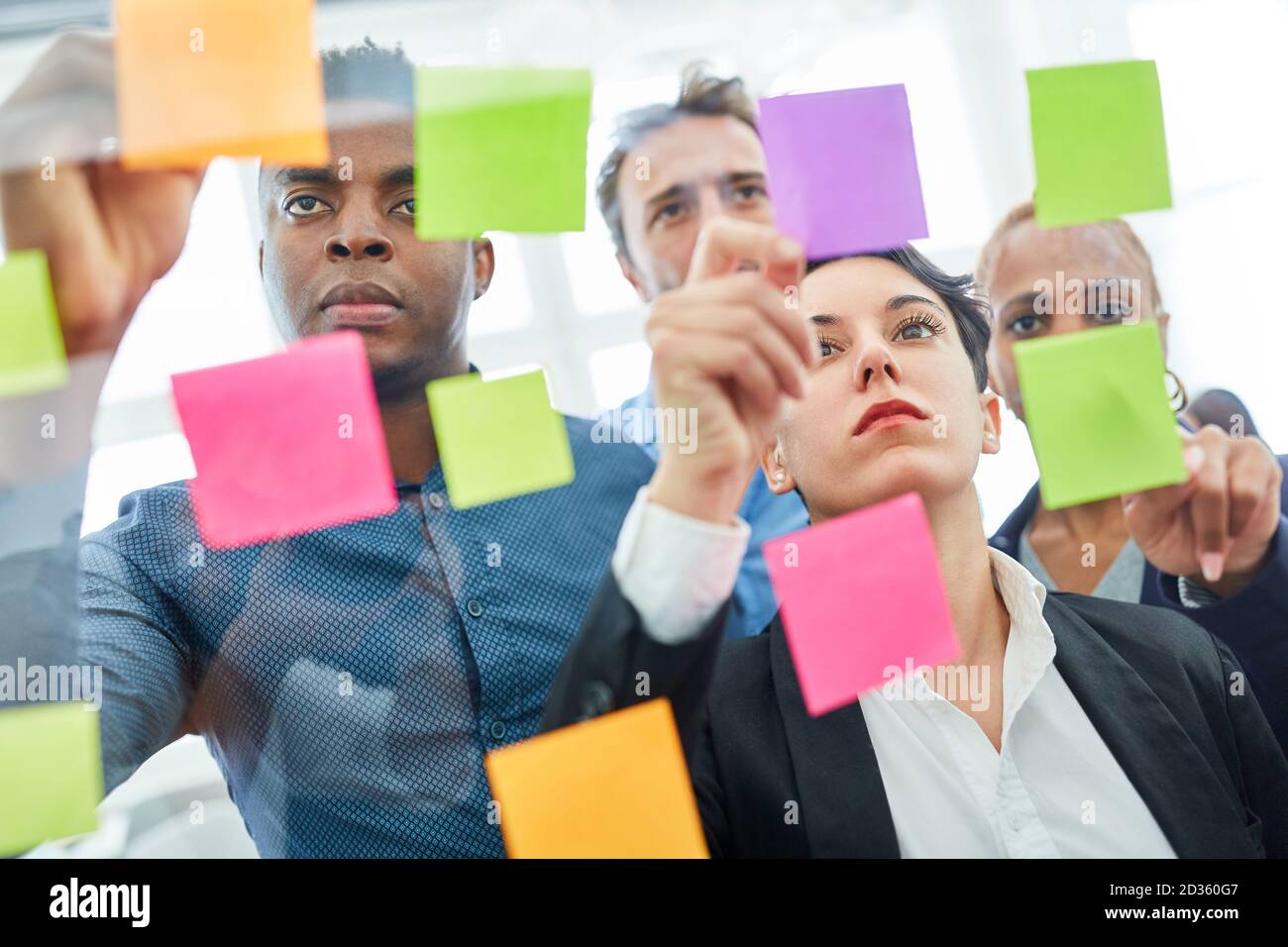 Un team creativo di start-up in un workshop di brainstorming con note appiccicose sul vetro Foto Stock