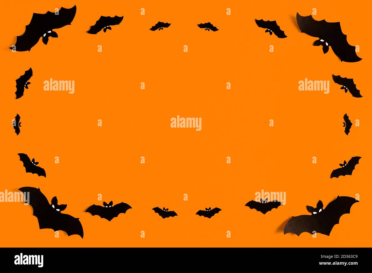 Silhouette di carta nera pipistrelli su uno sfondo arancione formando una cornice, un gregge di pipistrelli neri su uno sfondo arancione, concetto di Halloween, spazio di copia Foto Stock