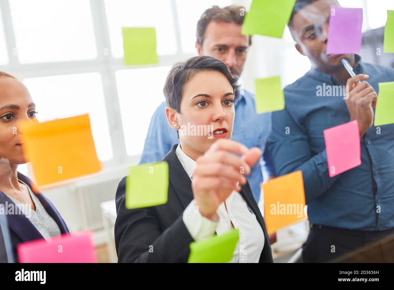 Team creativo in laboratorio di brainstorming con la ricerca di note appiccicose idee Foto Stock